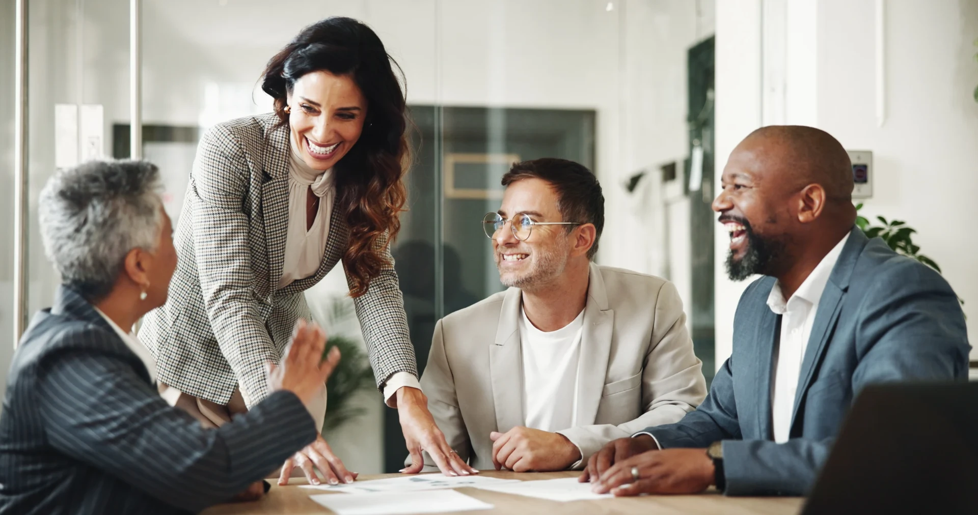 Diverse business team collaborating and laughing in a modern office meeting